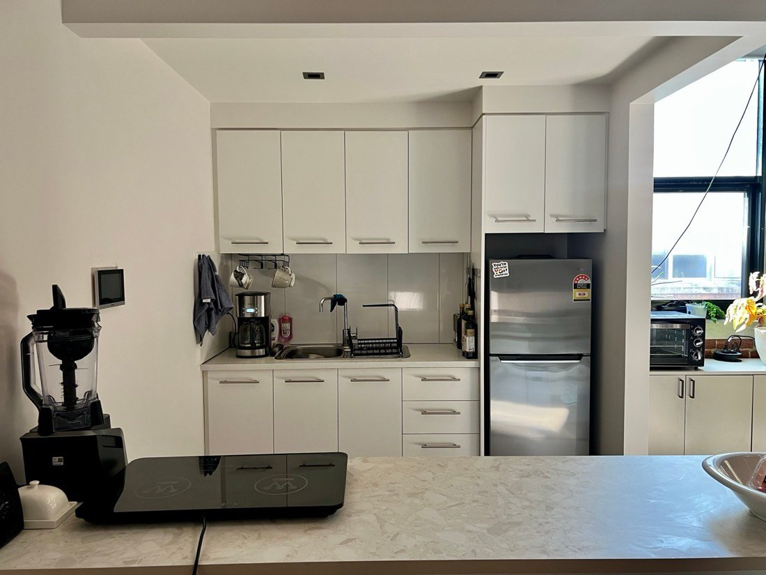 A white kitchenette with stovetop, oven, sink and fridge